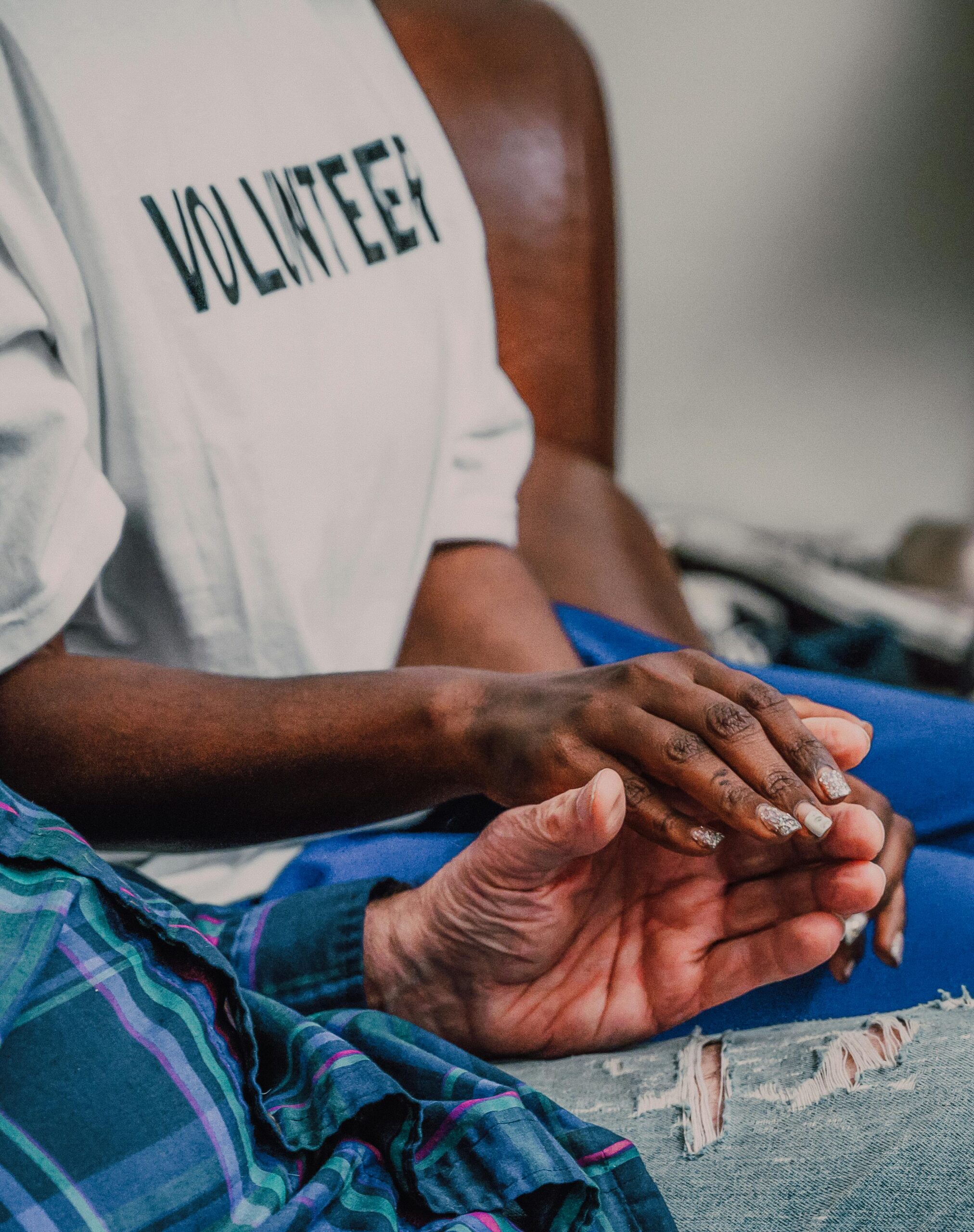 A volunteer offering comfort by holding hands with an elderly person, showcasing compassion.